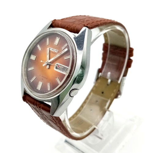 717 - A Vintage Seiko 5 Automatic Gents Watch. Brown leather strap. Golden orange toned dial with day/date... 