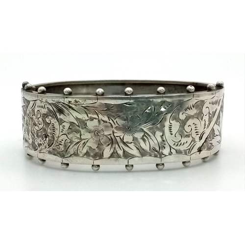 884 - A Victorian Sterling Silver Floral and Foliate Engraved Bangle. 17g. 23mm width.