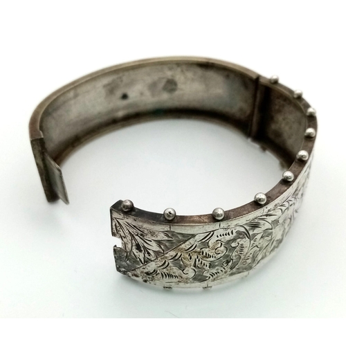 884 - A Victorian Sterling Silver Floral and Foliate Engraved Bangle. 17g. 23mm width.