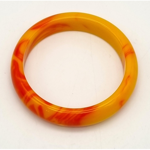 445 - A Red and Golden Coloured Jade Bangle. 6cm inner diameter.