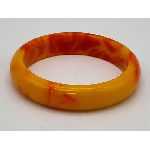 445 - A Red and Golden Coloured Jade Bangle. 6cm inner diameter.