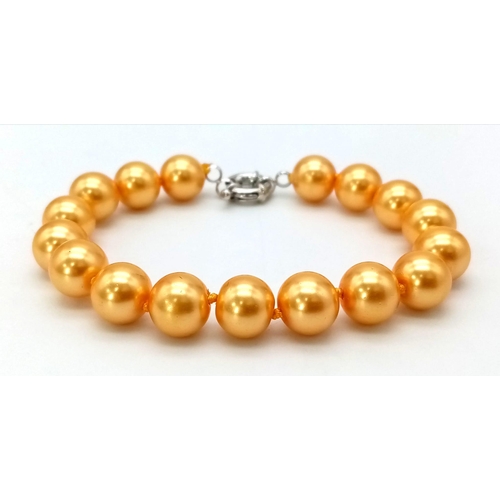 887 - A South Sea Pearl Shell Golden Necklace, Bracelet and Earring Set. 42cm. 16cm. 3cm drop.