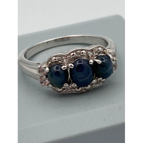 125 - SILVER RING having A trilogy of polished BLUE SPINEL cabochon set to top with WHITE TOPAZ  surround.... 