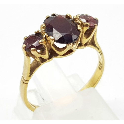 1061 - 9k yellow gold 3 stone garnet ring. 2.1g, size M.