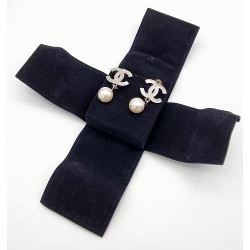 17 - A Pair of Chanel Monogram Pearl Earrings. Comes in a Chanel pouch with box. On white metal. 3cm drop... 