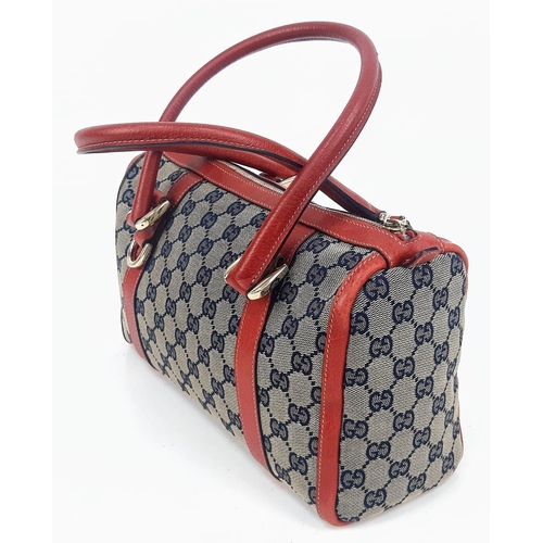 252 - A Gucci Monogram Canvas and Red Leather Boston Bag. Gilded hardware with zipped interior compartment... 