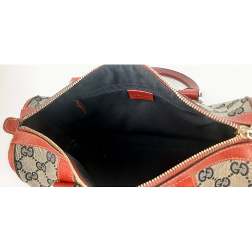 252 - A Gucci Monogram Canvas and Red Leather Boston Bag. Gilded hardware with zipped interior compartment... 