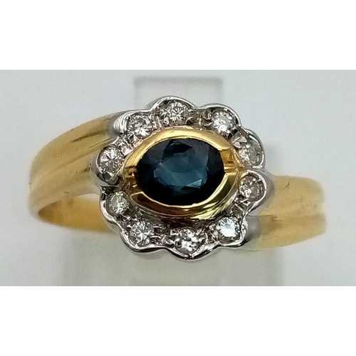 114 - An 18k Yellow Gold Sapphire and Diamond Ring. Central oval sapphire with a halo of clean round cut d... 