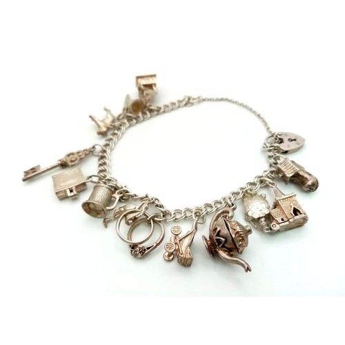 813 - A Vintage 925 Silver Charm Bracelet with Heart Clasp and Twelve Charms. 37.7g total weight.