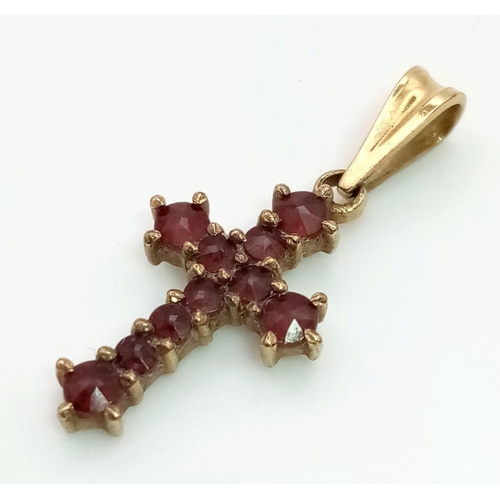 563 - A 9 K yellow gold cross with garnets. Dimensions (with bail): 25 x 10 x 2 mm , weight: 1 g.