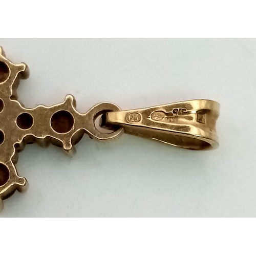 563 - A 9 K yellow gold cross with garnets. Dimensions (with bail): 25 x 10 x 2 mm , weight: 1 g.