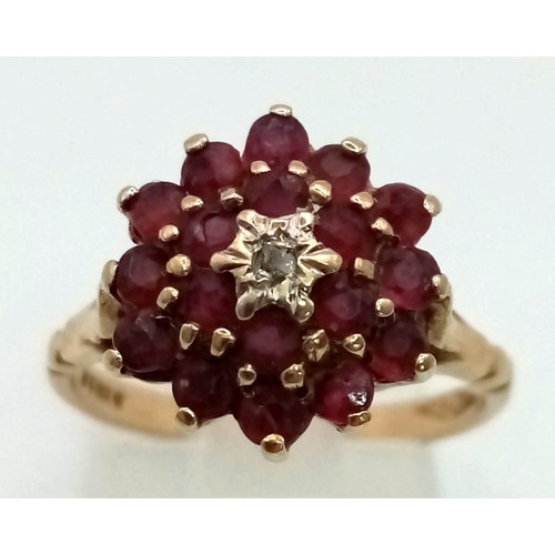 570 - A 9 K yellow gold ring with a cluster of rubies and a central diamond. Ring size: N, weight: 2.96 g.