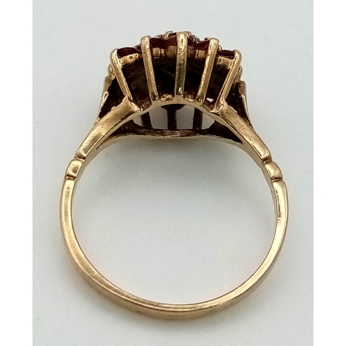 570 - A 9 K yellow gold ring with a cluster of rubies and a central diamond. Ring size: N, weight: 2.96 g.