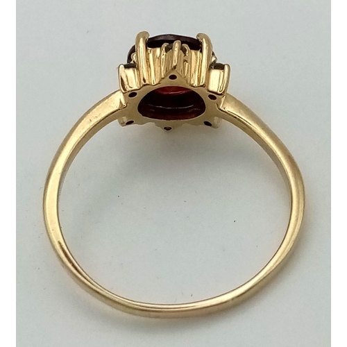 567 - An Antique 9k Yellow Gold Red and Green Garnet Ring. Central blood red garnet with a halo of six sma... 