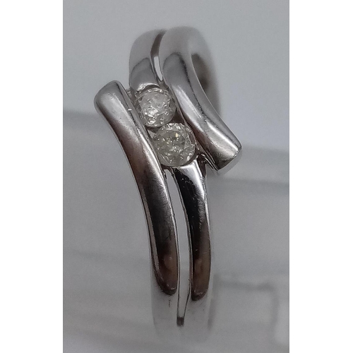 715 - A 9K White Gold Crossover Diamond Ring with 2 Diamonds in the center. Size O. Total weight: 2.66g