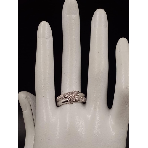 1003 - An 18K White Gold Diamond Cluster Crossover Ring.
Size O. 5.69g.