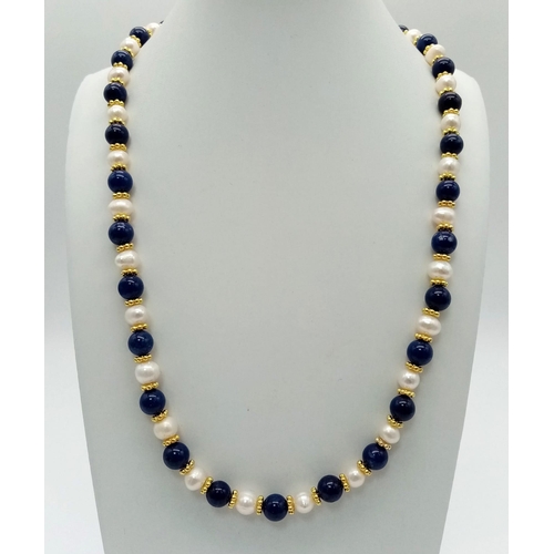 400 - A Freshwater Pearl and Lapis Lazuli Bead Necklace. 8mm beads. Gilded spacers and clasp. 66cm