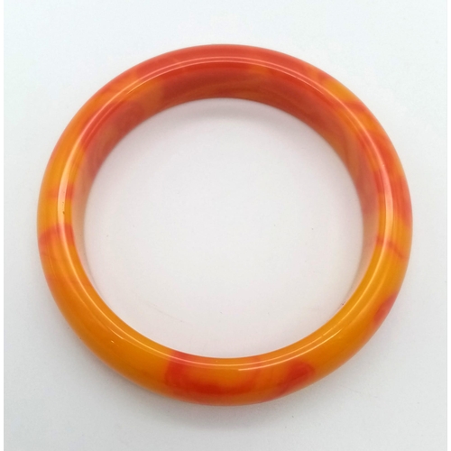 421 - A Red and Orange Swirl Jade Bangle. 6cm inner diameter. 16mm width.