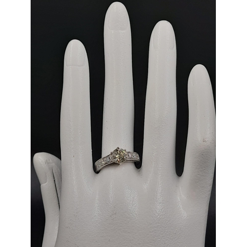 410 - A Platinum Diamond Ring - Central stone with small baguette-cut diamonds on shoulders. Size M. 7.86g