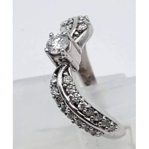 610 - A 9K White Gold Diamond Wave Ring. Centre diamond with diamond waves either sides. 0.75ct Size L. 3g... 