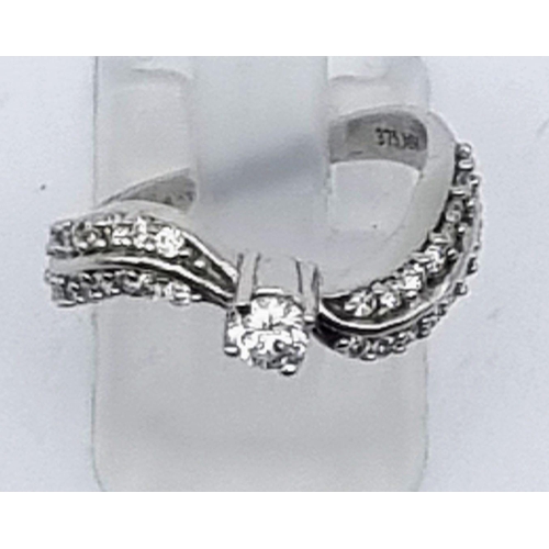 610 - A 9K White Gold Diamond Wave Ring. Centre diamond with diamond waves either sides. 0.75ct Size L. 3g... 