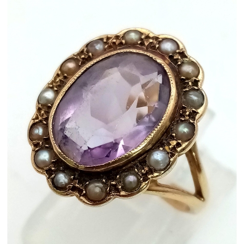 1068 - A vintage, 9K yellow gold ring with an oval cut amethyst surrounded by a halo of seed pearls. Ring s... 