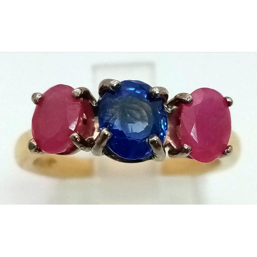 1012 - An 18K yellow gold ring with central blue sapphire and a ruby on either side. Ring size: M, weight: ... 