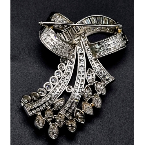 44 - A 6ct Diamond and Platinum Bow Brooch. Brilliant cut baguette, round cut and encrusted diamonds crea... 