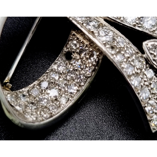 44 - A 6ct Diamond and Platinum Bow Brooch. Brilliant cut baguette, round cut and encrusted diamonds crea... 