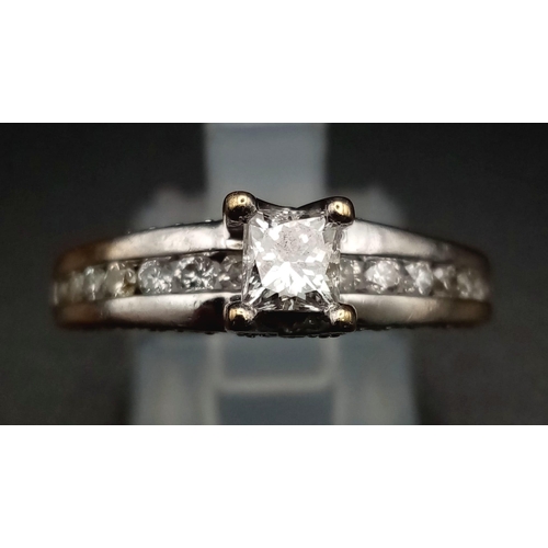 871 - An 18K White Gold Diamond Ring. Princess cut central diamond with further compliments of diamonds on... 