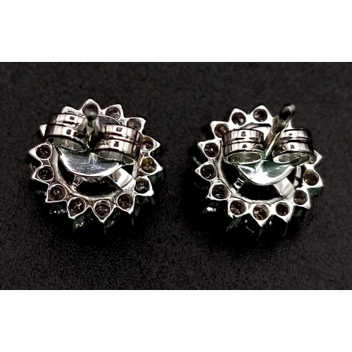 565 - A Pair of Platinum Diamond Floral Stud Earrings. Central diamond cabochon surrounded by a halo of di... 