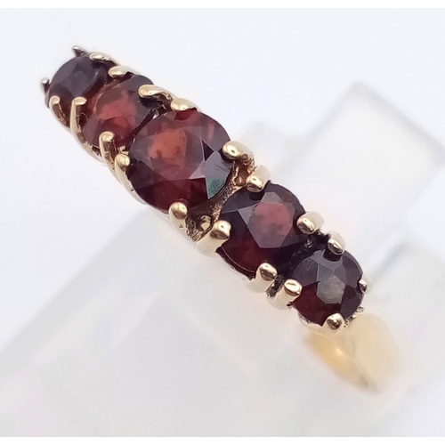 849 - A 9K Yellow Gold and Garnet Ring. Five bright garnets. Size N/O. 2g total weight.