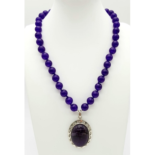 542 - An Amethyst Bead Necklace with Amethyst Oval Pendant. 22 and 5.5cm. Beads - 10mm.