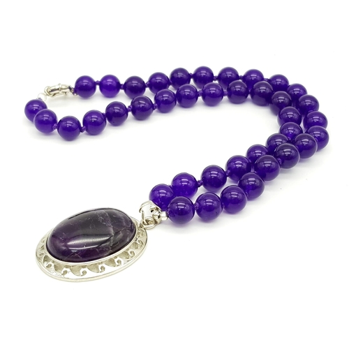 542 - An Amethyst Bead Necklace with Amethyst Oval Pendant. 22 and 5.5cm. Beads - 10mm.