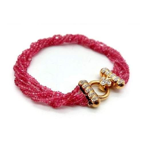 396 - An 18K Gold, Diamond and Ruby Four Strand Bracelet. Four twisted strands of pink rubies with a gold ... 