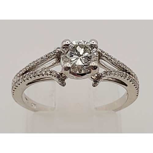 152 - A 10K White Gold Diamond Solitaire Ring with Diamond set split shoulders. Size N/M. Weight: 2.2g