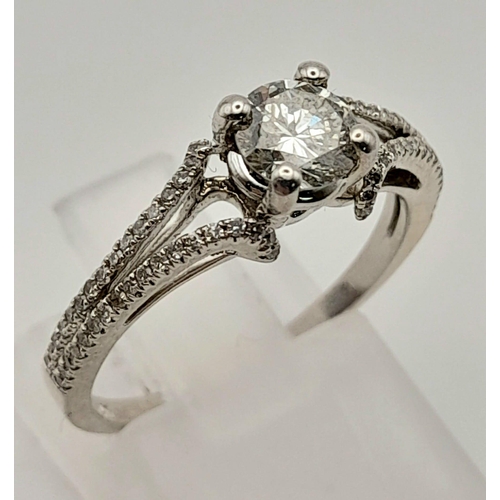 152 - A 10K White Gold Diamond Solitaire Ring with Diamond set split shoulders. Size N/M. Weight: 2.2g