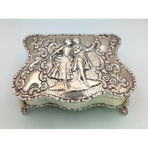23 - An Antique  Silver Trinket Box. A romantic repoussé scene on lid. Four claw feet. A lovely piece in ... 