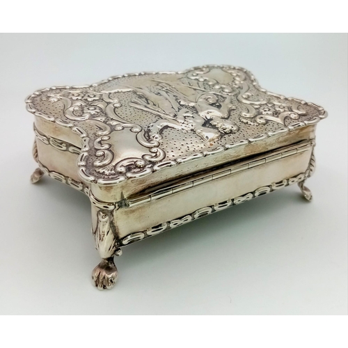 23 - An Antique  Silver Trinket Box. A romantic repoussé scene on lid. Four claw feet. A lovely piece in ... 