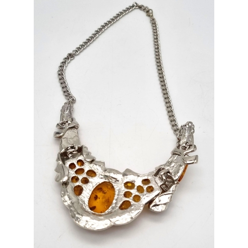 196 - An ART DECO white metal (untested) and amber necklace accompanied by an amber ring (size: N1/2). 
Ne... 