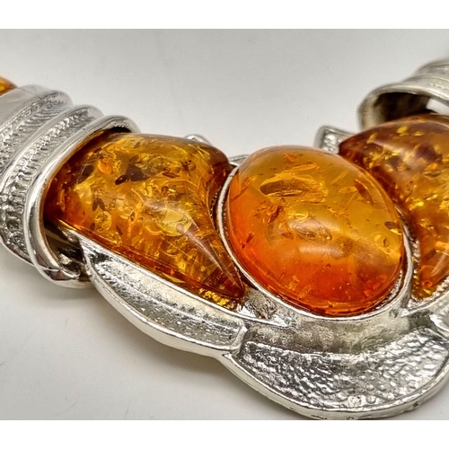 196 - An ART DECO white metal (untested) and amber necklace accompanied by an amber ring (size: N1/2). 
Ne... 