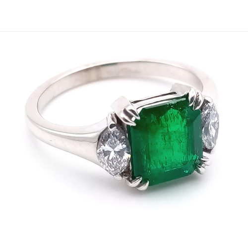 66 - An 18K White Gold, Emerald and Diamond Ring. Emerald-cut centre stone with a marquise cut diamond ei... 