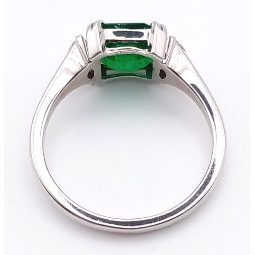 66 - An 18K White Gold, Emerald and Diamond Ring. Emerald-cut centre stone with a marquise cut diamond ei... 