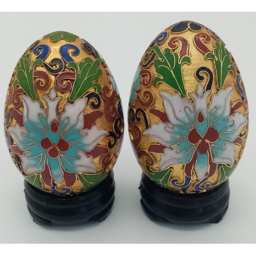 279 - Two very ornamental Chinese cloisonné eggs on wooden base. Height: 7 cm