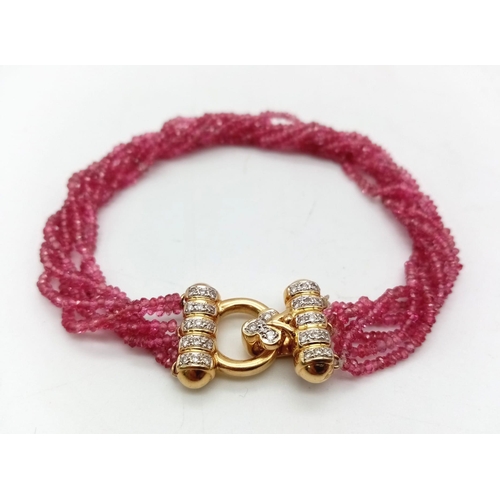 1208 - An 18K Gold, Diamond and Ruby Four Strand Bracelet. Four twisted strands of pink rubies with a gold ... 