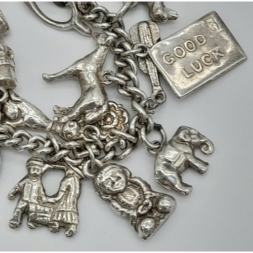 447 - A Vintage Silver Charm Bracelet. Over 20 charms. 72.43g total weight.