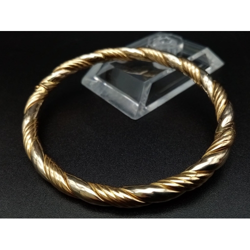 7 - A Classic Vintage 18K Yellow Gold Bangle. Geometric rope-twist decoration. Clip open clasp. 6cm inne... 