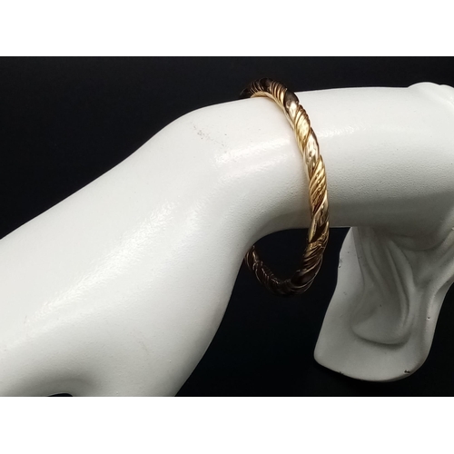 7 - A Classic Vintage 18K Yellow Gold Bangle. Geometric rope-twist decoration. Clip open clasp. 6cm inne... 