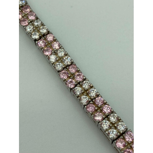 27 - Hallmarked SILVER TENNIS BRACELET, set with double lines of Sparkling Pink and White zirconias. 19 c... 