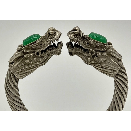 777 - A Tibetan Silver Twin Dragon Twisted Bangle/Bracelet with Green Jade head decoration. 7cm inner diam... 